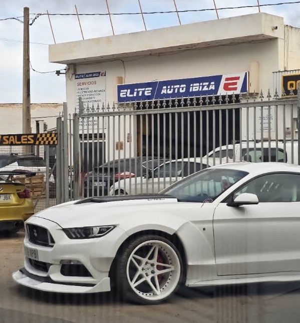 Fachada de nuestro taller con el rótulo Elite Auto Ibiza y un Ford Mustang blanco